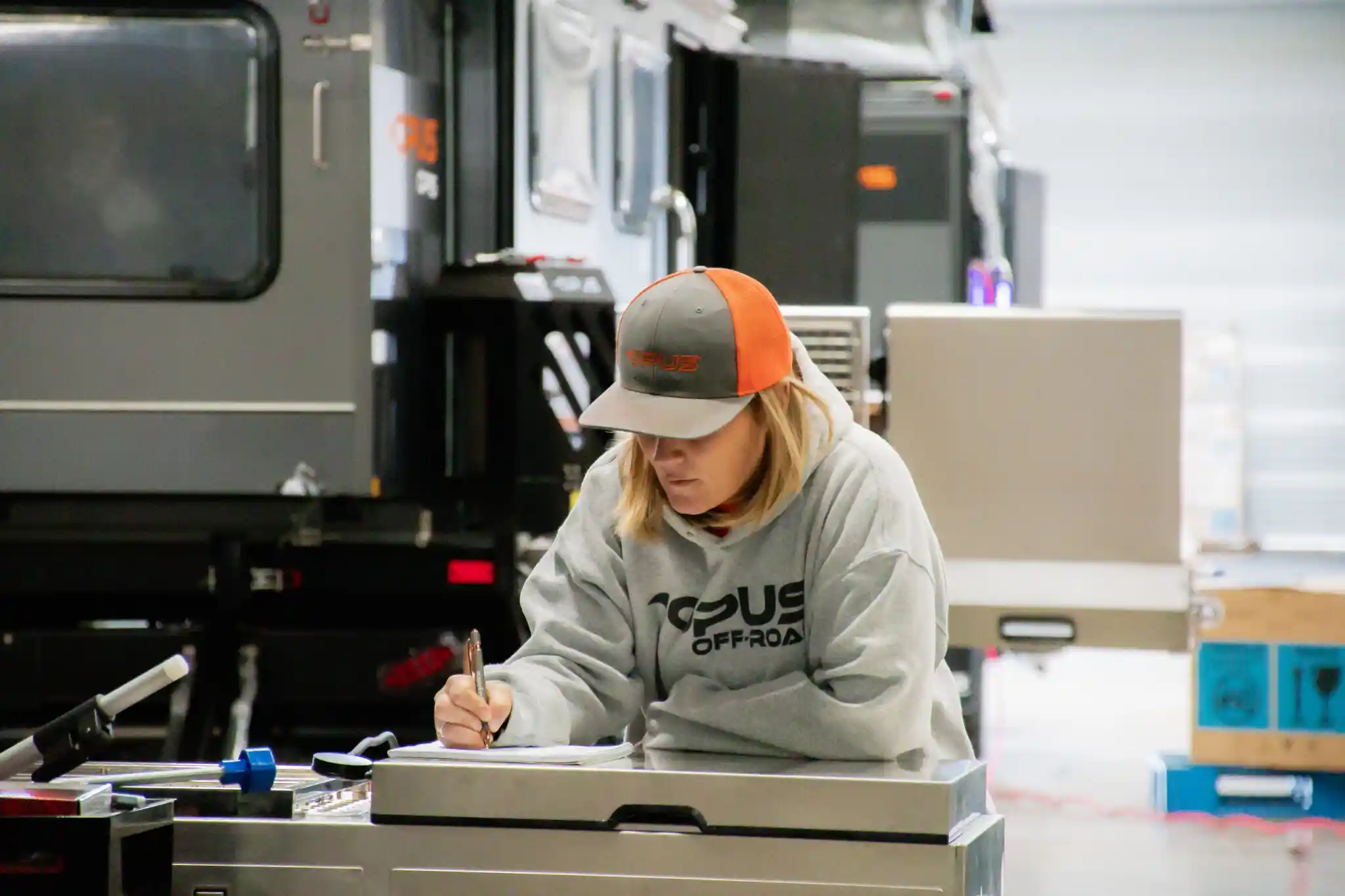 An OPUS team member signing off paperwork beside a camper on the production line