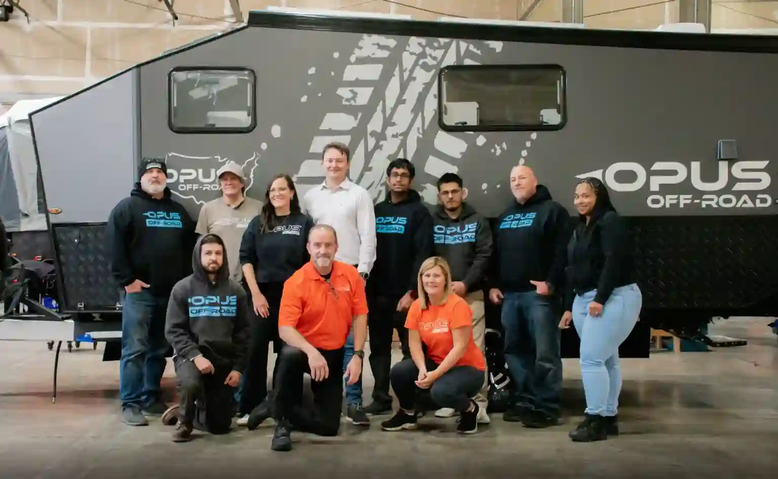 OPUS Camper team members together in the warehouse in front of a camper