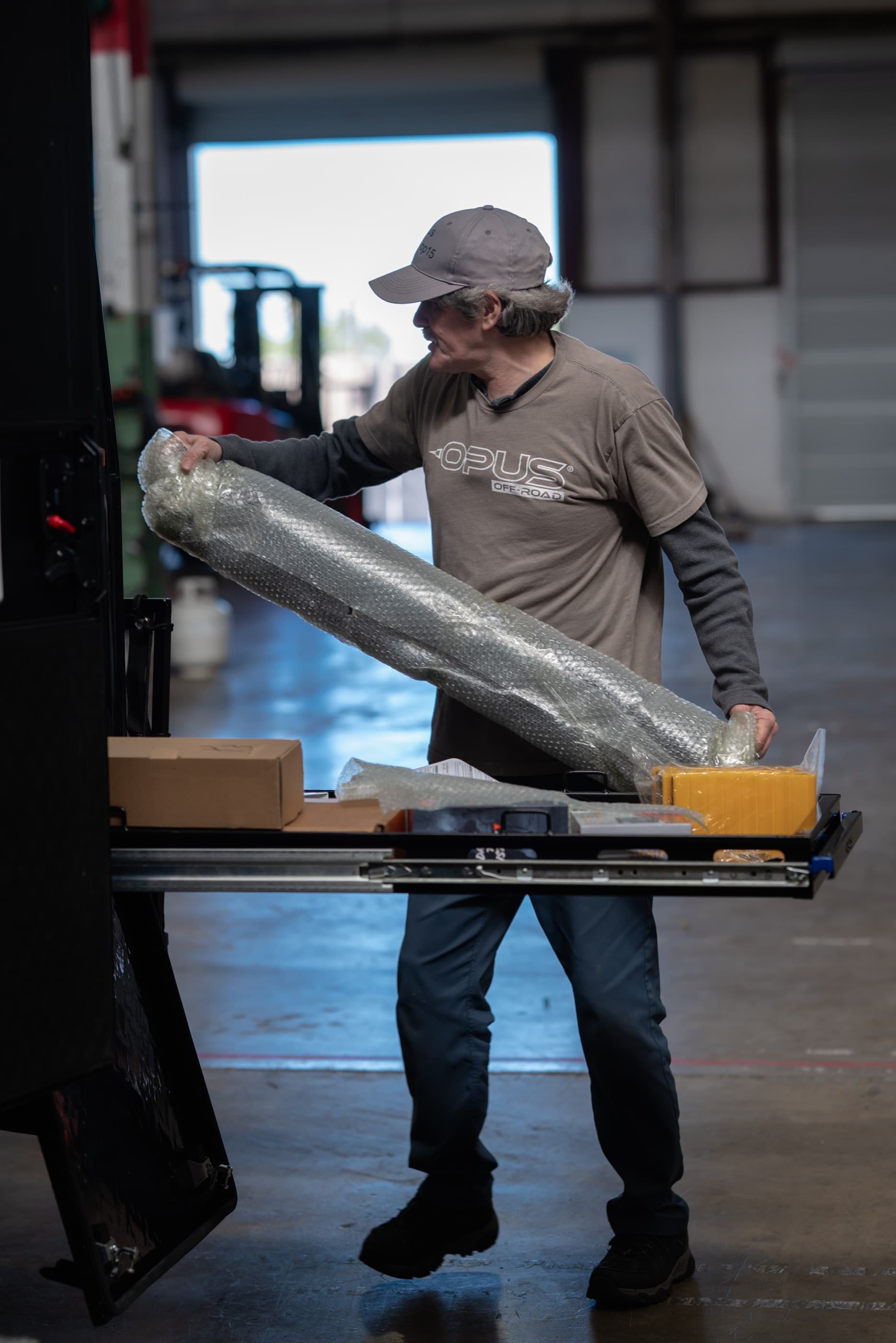 An OPUS team member carrying a rolled tent component across the factory floor