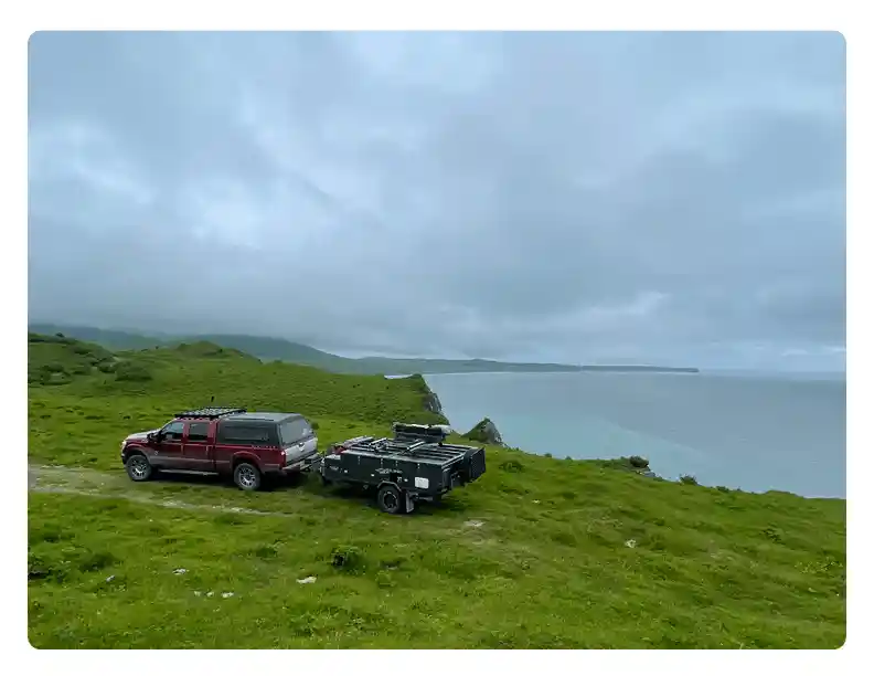 OPUS camper off road setup on grassy hill near coastal view